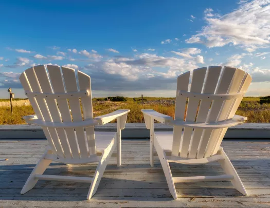 Two white chairs on an outdoor patio, looking out to a large valley