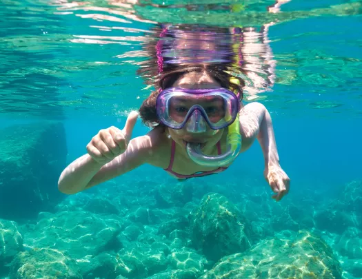 Girl scuba diving in the ocean, with her thumb up