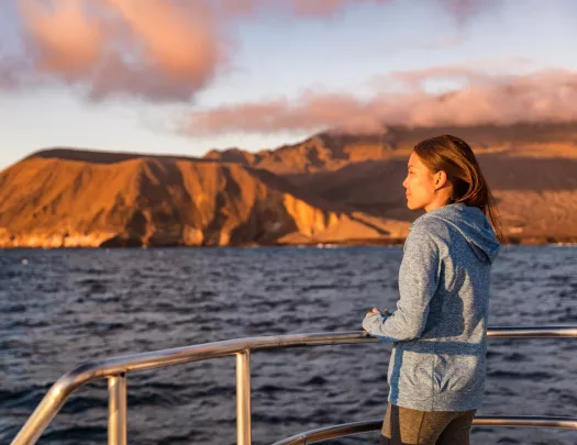 Woman standing on a boat, looking out to the ocean