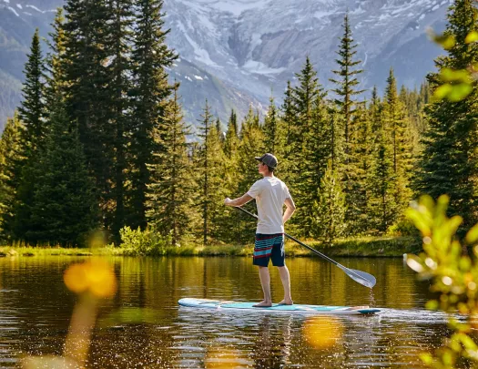 paddleboarder on a calm lake surrounded by trees