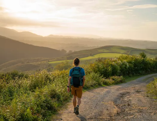 Man descending a dirt trail with the sunset in the background