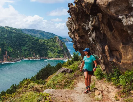 Woman hiking on a dirt trail and looking back towards a river
