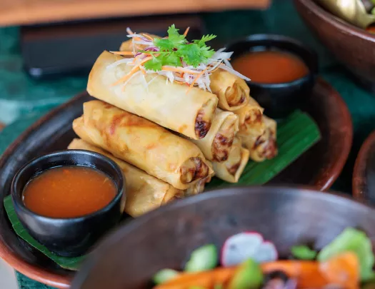 Plate of fried eggrolls with a bowl of red sauce
