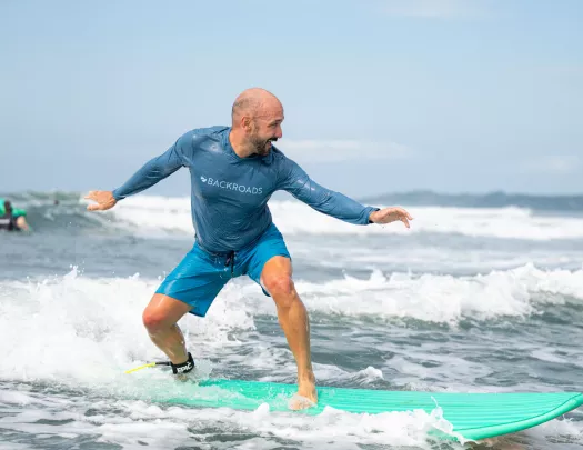 Man smiling while standing on top of a surfboard