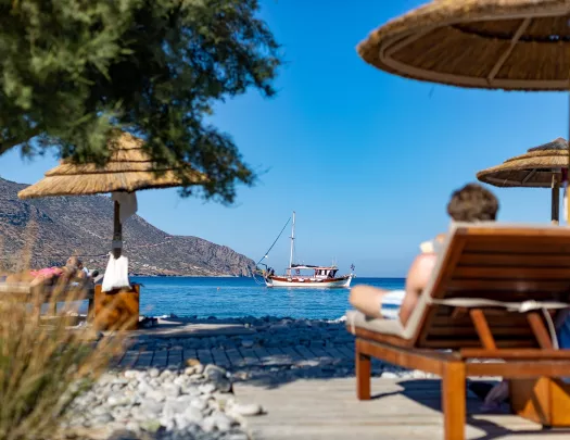People sitting on reclining chairs by the shore of an ocean