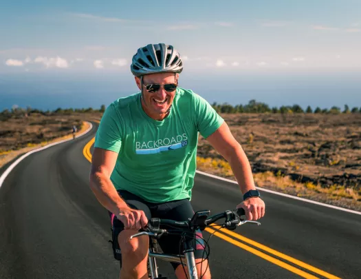 Man smiling while riding a bike on an empty road
