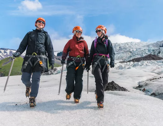 Three people wearing snow gear, walking through a icy trail