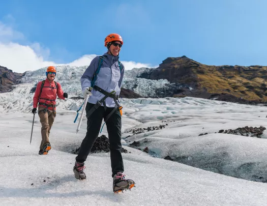 Two hikers walking through a snowy mounds on a trail