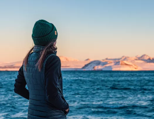 Woman wearing a beanie looking out towards a lake