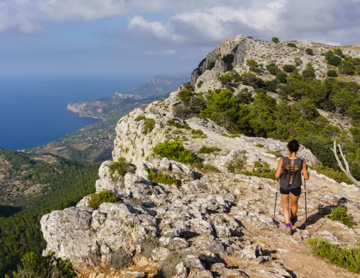 Woman with hiking poles, walking on a large mountain