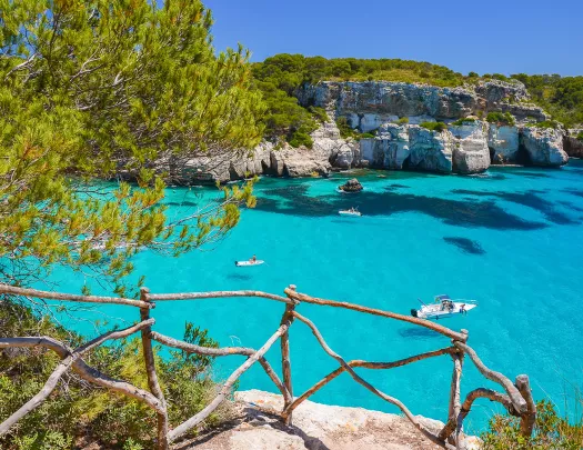 Stone path with view of clear blue water and boats floating in the ocean