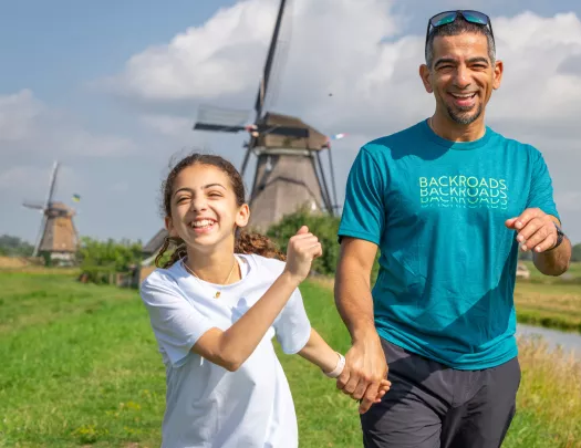 Man holding hands with his daughter, walking through a grassy field