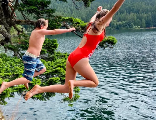 Man and woman jumping off a cliff into a lake