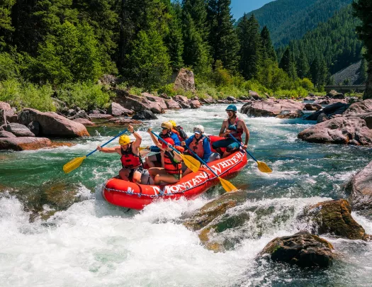 Group of people on a red raft, paddling 
