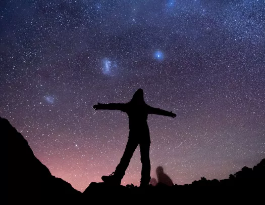 Silhouette of woman with her arms open with the stars in the sky