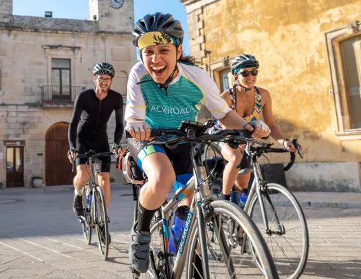 Two women and one man riding their bikes and smiling