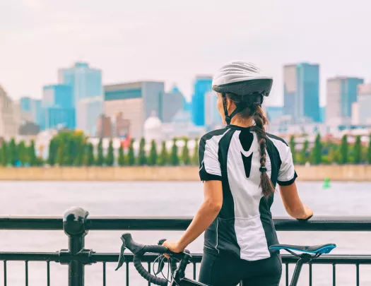 Woman standing next to her bike, looking out to a city and a river