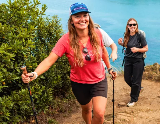 Two women with walking poles ascending a sandy path