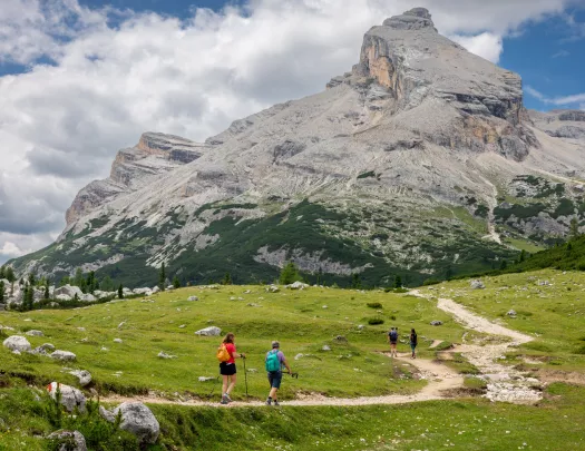 Group of people hiking on a dirt trail, towards a large mountain