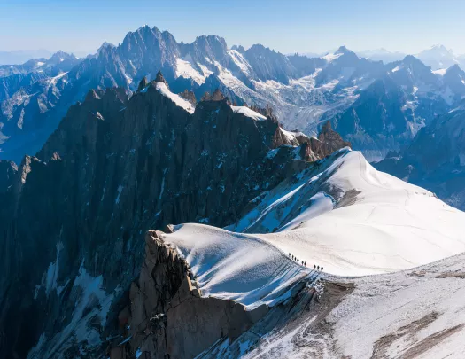 Top view of snowcapped mountains with larger mountains in the distance