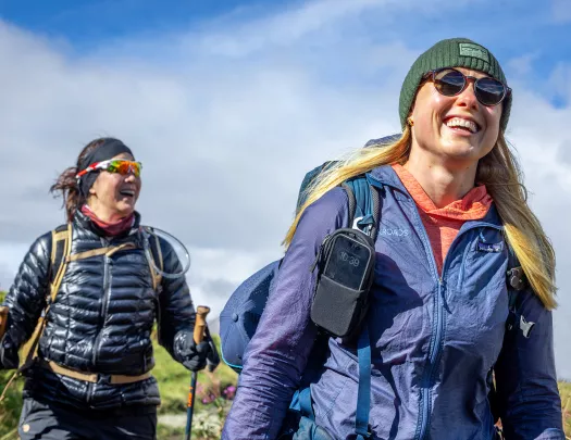 Two women smiling while hikings in an open field