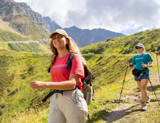 Two women smiling while walking on a dirt and grass trail