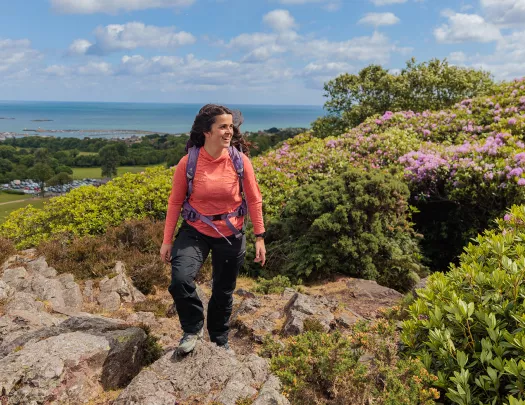 Woman wearing a pink shirt and a backpack, hiking on a rocky hill
