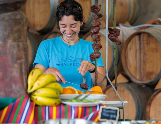 Woman smiling while grabbing meat from a large, metal skewer