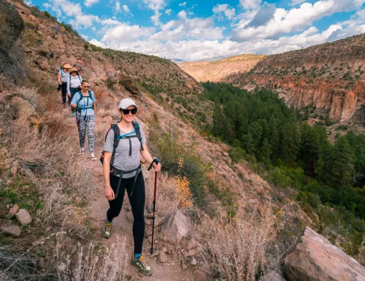 Group of women with walking poles descending a dirt trail