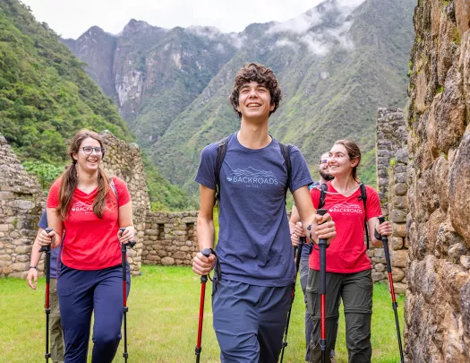 Group of men and women with walking poles, walking through stone ruins