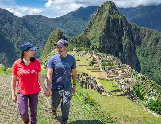 Man and women holding hands, with sights of Machu Picchu in the background