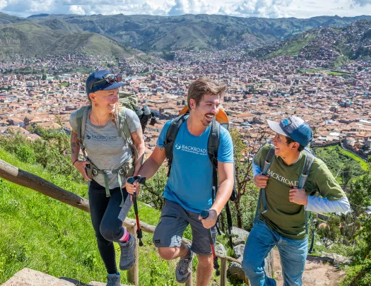 Two men and one women climbing up stairs with a view of a town in the distance