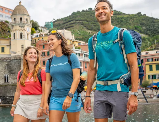 Two women and one man smiling while walking on a boat dock by the water