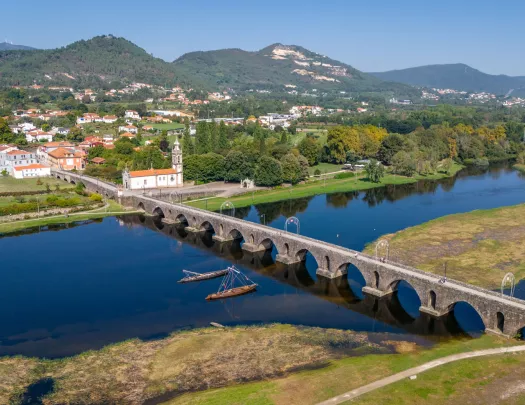 Long stone bridge with a river underneath, leading to a small town
