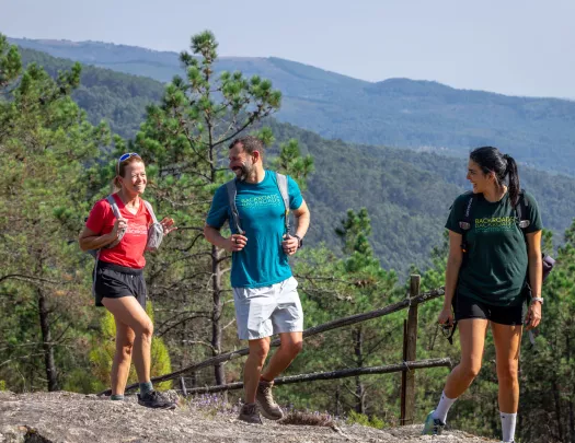 Man and two women smiling while hiking on top of a hill