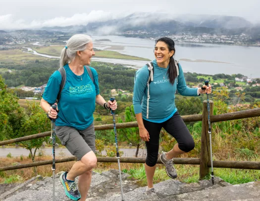 Two women smiling while walking up stairs on a hill