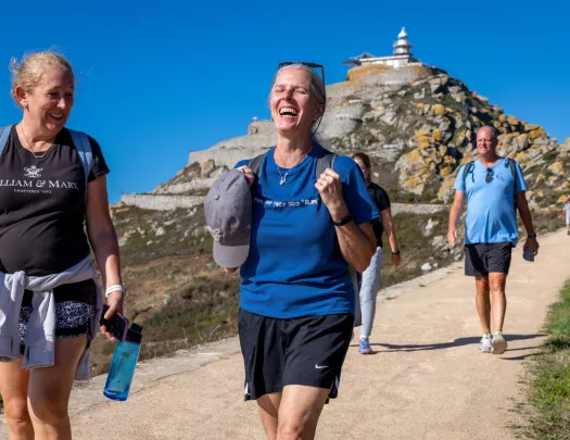 Group of men and women walking on a stone path with a large cliff in the background