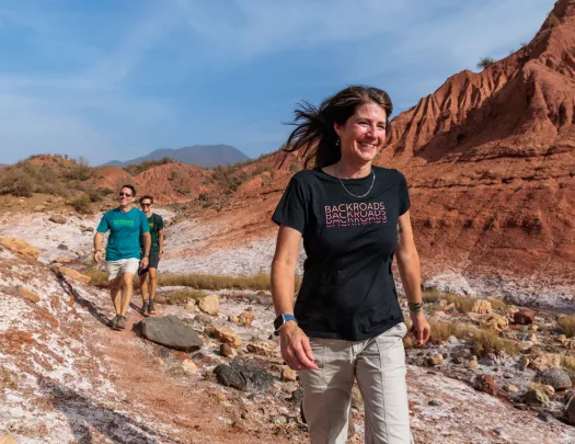 Woman and two men walking on a dirt trail, smiling