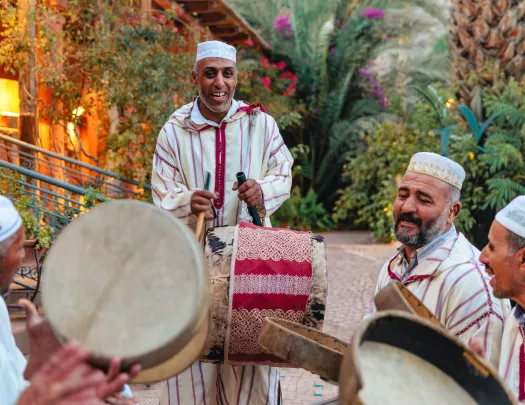 Group of men wearing white, playing bongo-like instruments