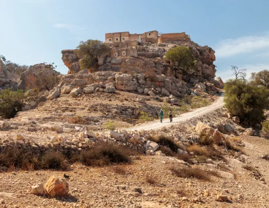 People in the distance walking up a trail on a cliff