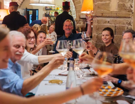 Group of people smiling while raising their glasses around a dining table
