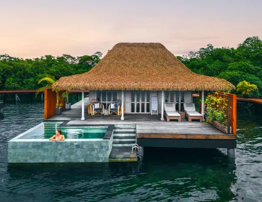 Woman sitting in an outdoor pool outside of a cottage