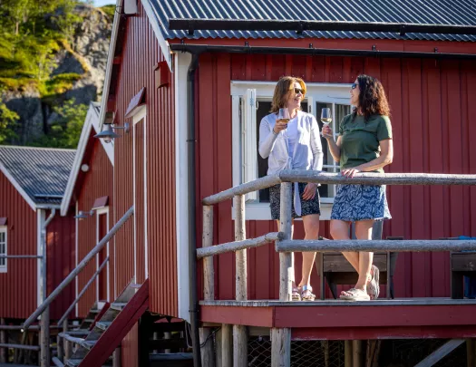Two women holding wineglasses while smiling in front of a red building