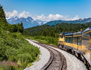 Yellow train with mountains in the background in Alaska