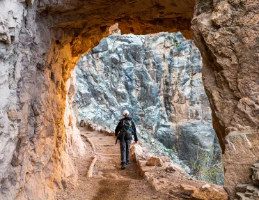 Archway shot of guest hiking down trail, towards rock face.