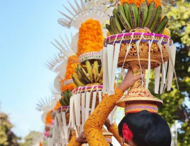 Procession of beautiful Balinese women in traditional costumes - sarong, carry offering on heads for Hindu ceremony.