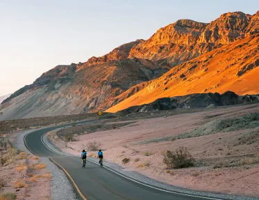 Guests riding down desert road during sunset.