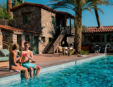 Guests relaxing poolside at desert resort.