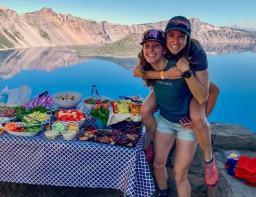 Two guests/leaders next to lunch spread, one is on the other's back.