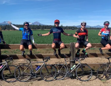 Five guests and their bikes, sitting on a large fence.